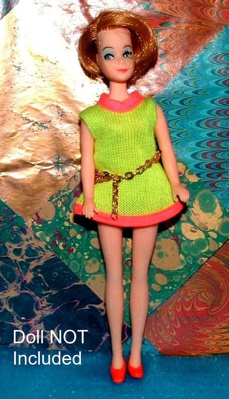 the doll is wearing a bright green dress and red high heeled shoes with a gold chain around her ankles