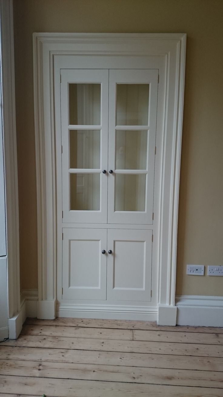 an empty room with wooden floors and white cupboards