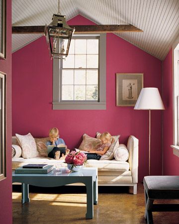 two children sitting on a couch in a living room with pink walls and flooring