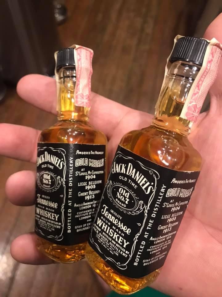 two bottles of jack daniels whiskey sitting in someone's hand