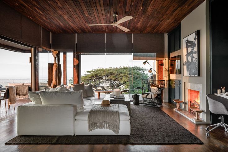 a living room filled with furniture and a fire place in front of a large window