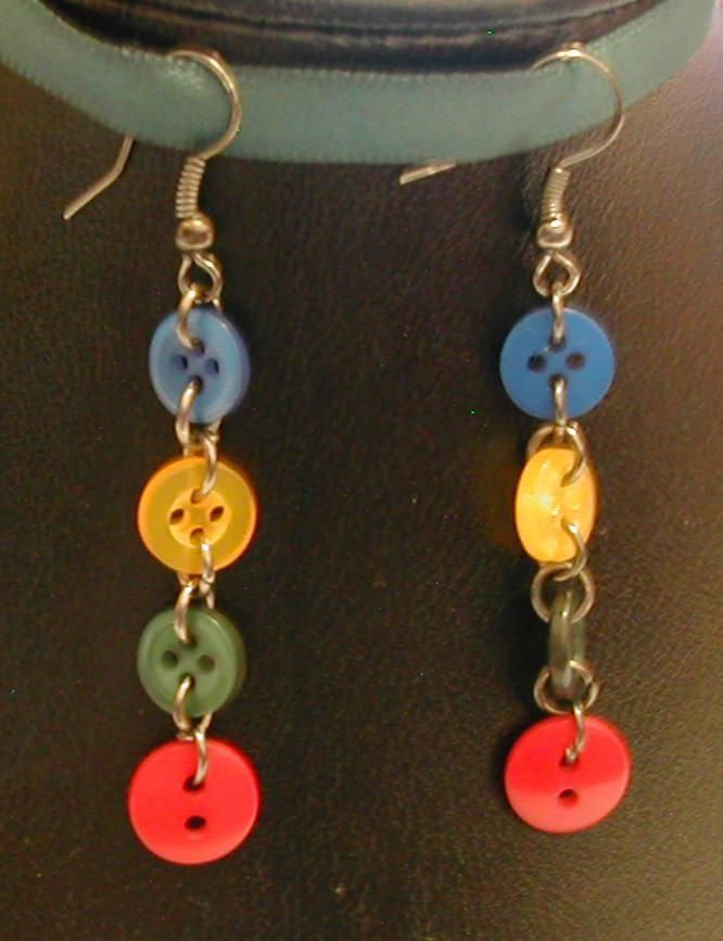 two pairs of earrings with colorful buttons hanging from it's earwires on a table