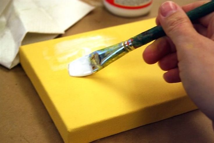 a person is holding a paintbrush in their left hand and painting on a yellow board