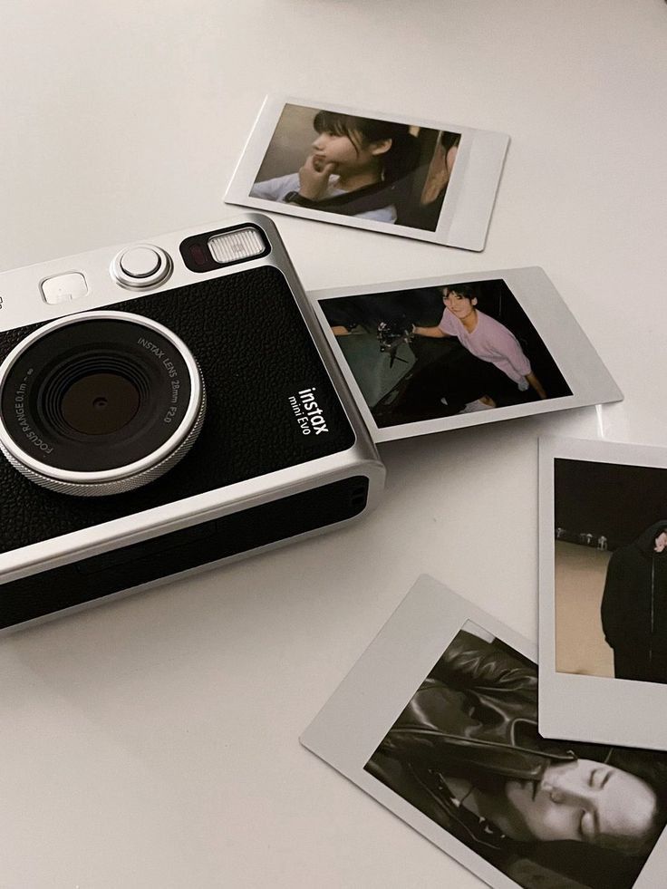 a camera sitting on top of a white table next to polaroid pictures and photos