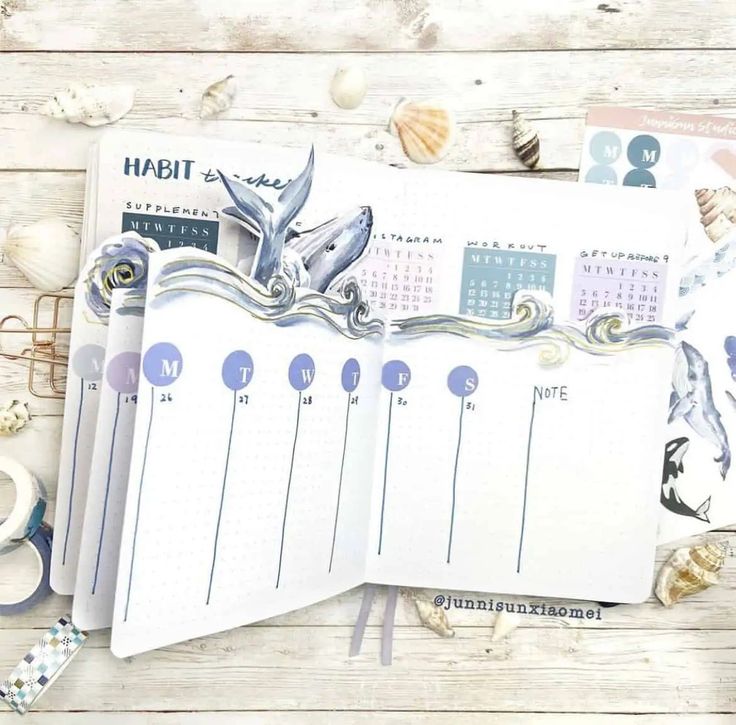 an open planner sitting on top of a wooden table next to shells and seashells