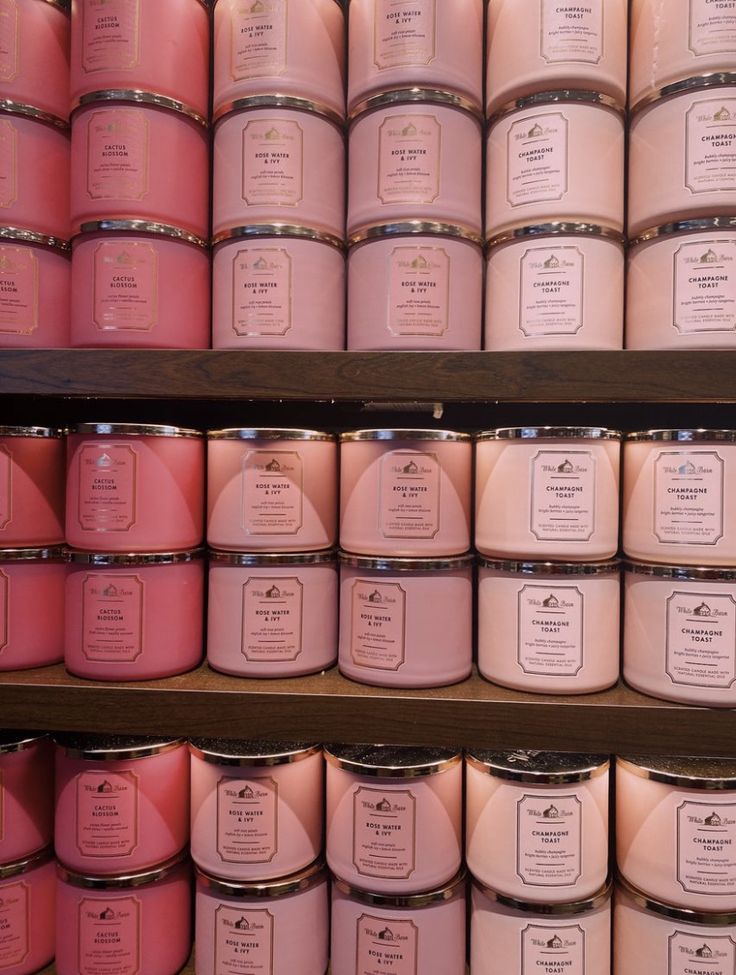 several rows of pink candles on shelves in a store, with labels and price tags