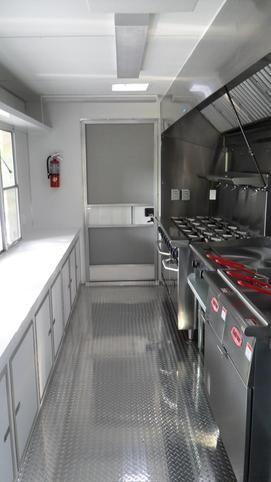 an empty kitchen with stainless steel appliances and white counter tops, along with large windows