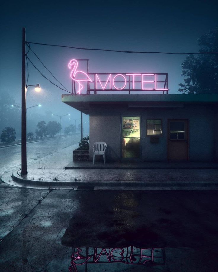 a motel sign lit up in the dark on a foggy night with chairs outside