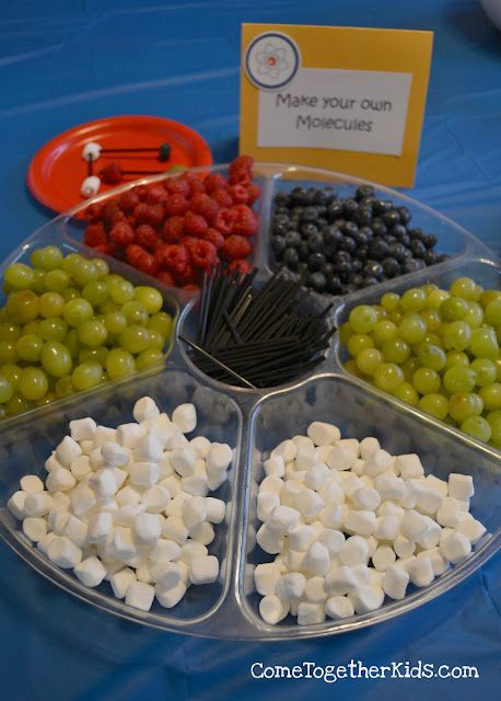 grapes, raspberries, and marshmallows are arranged in trays on a table