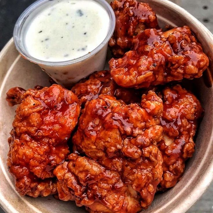 a bowl filled with fried food next to a cup of sauce