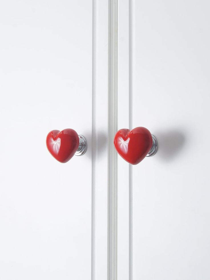 two red heart shaped knobs on a white door