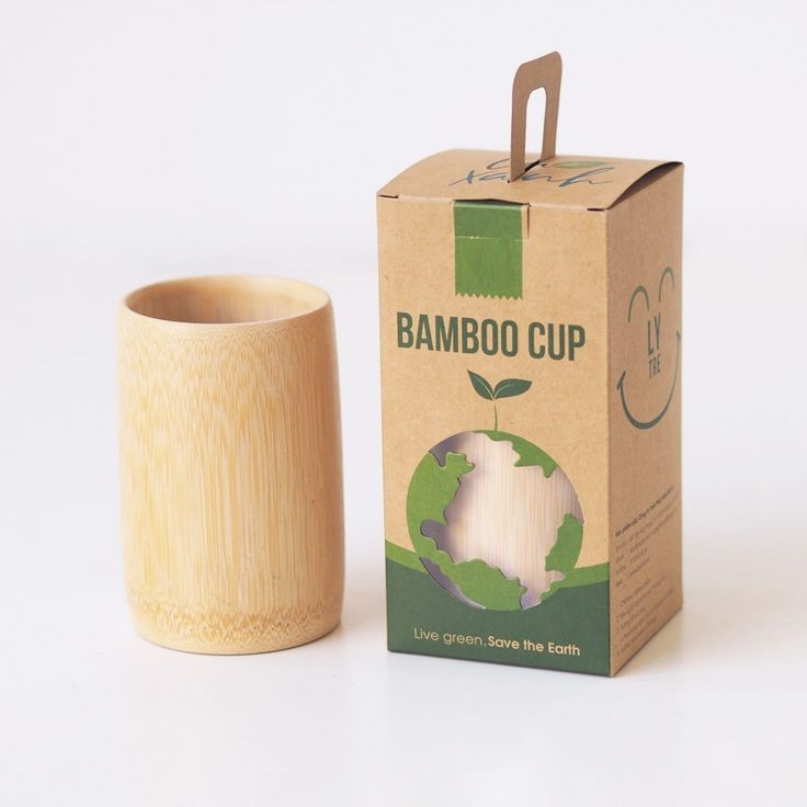 a bamboo cup sitting next to a cardboard box on a white surface with clippings