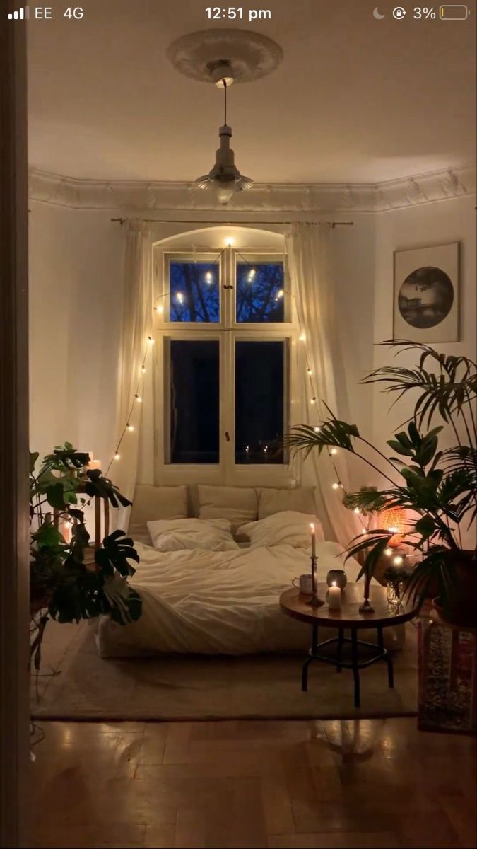 a bed sitting in the middle of a living room next to a table with candles on it