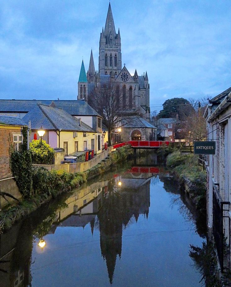 a river running through a small town next to a tall building with a cathedral in the background