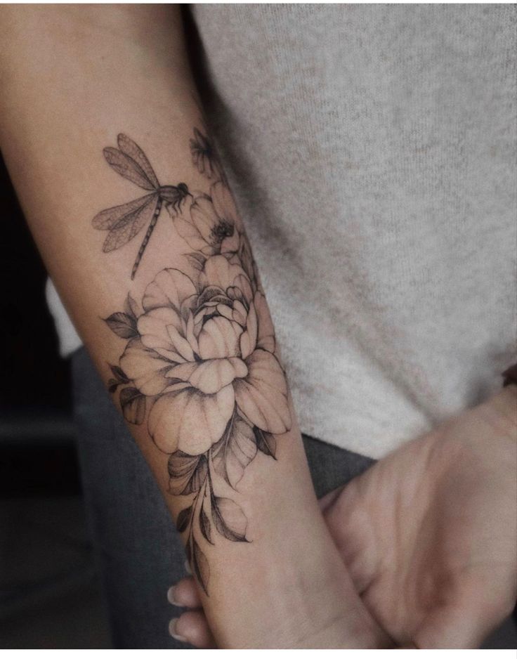 a woman's arm with flowers and dragonflies on it