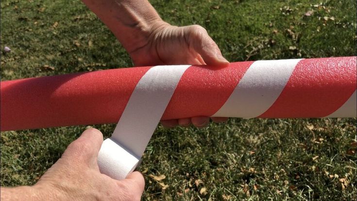 a person is holding a red and white striped pole