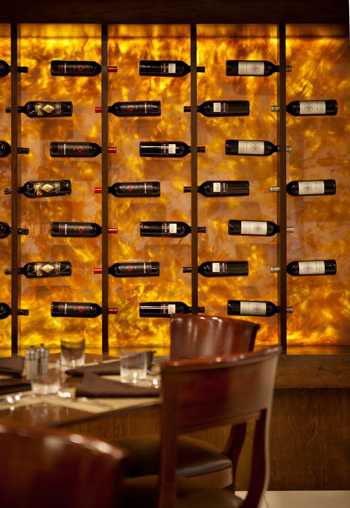 the wine bottles are lined up on the wall next to the chairs and table in front of it