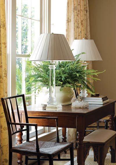 a table with two chairs and a lamp on top of it next to a window