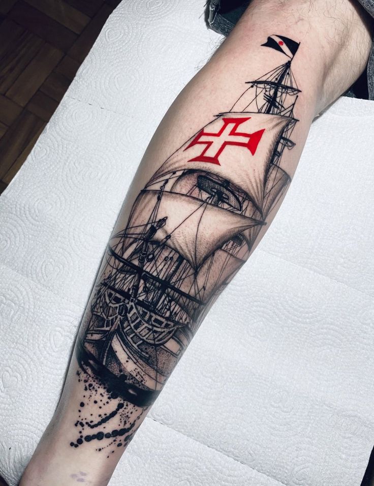 a man's arm with a ship on it and an anchor in the middle