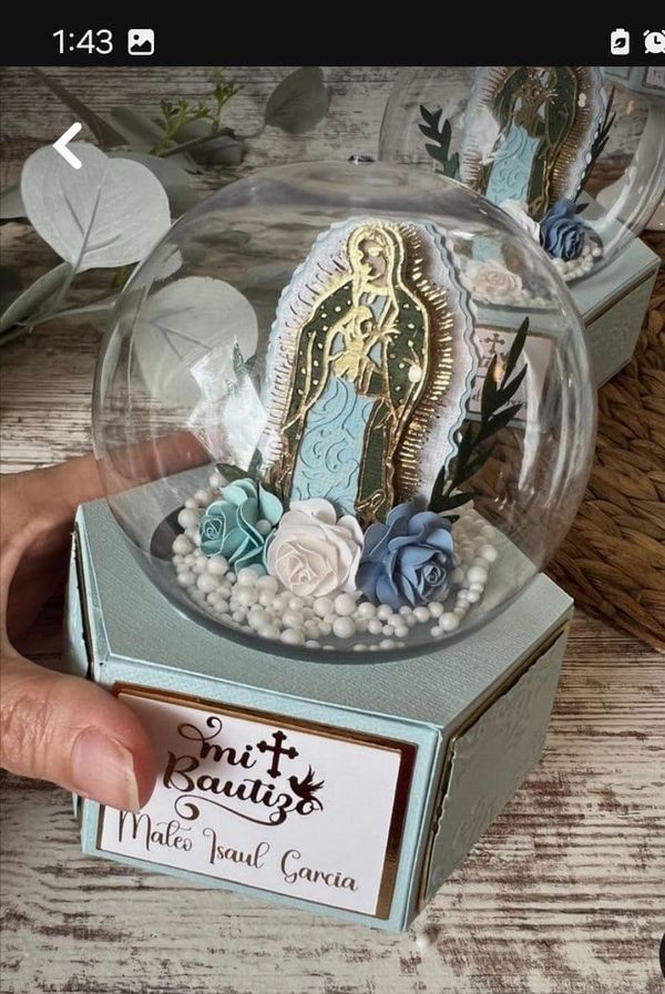 a hand holding a glass ball with some decorations in it on top of a wooden table