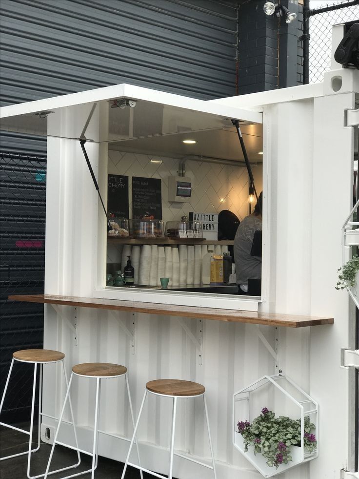 an outdoor bar with three stools next to it and a man behind the counter