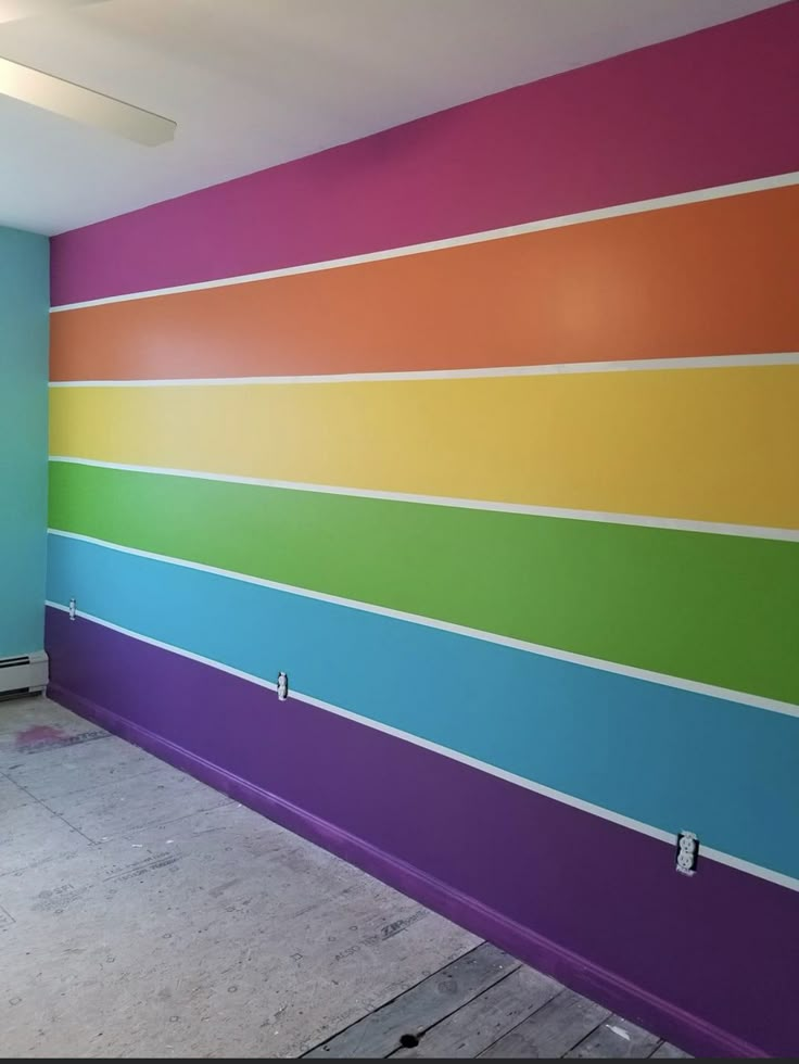 an empty room with rainbow painted on the wall and flooring in front of it