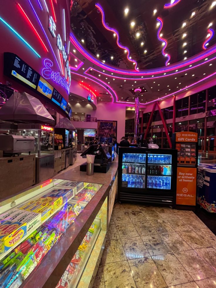 the inside of a restaurant with neon lights and soda machines on display in front of them