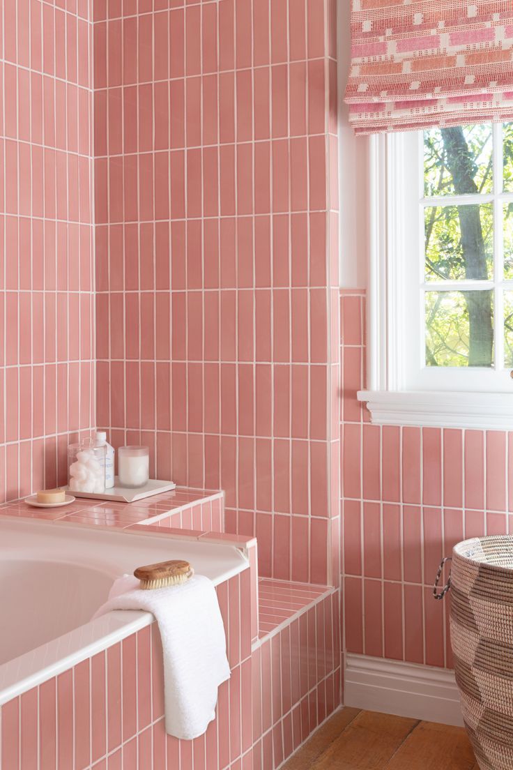 a bathroom with pink tiles on the walls and floor, along with a bathtub