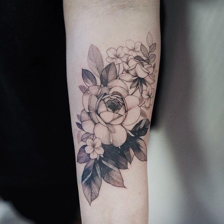 a black and white flower tattoo on the arm