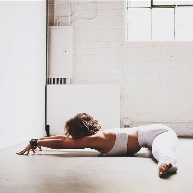 a woman laying on the floor with her arms behind her back and legs spread out