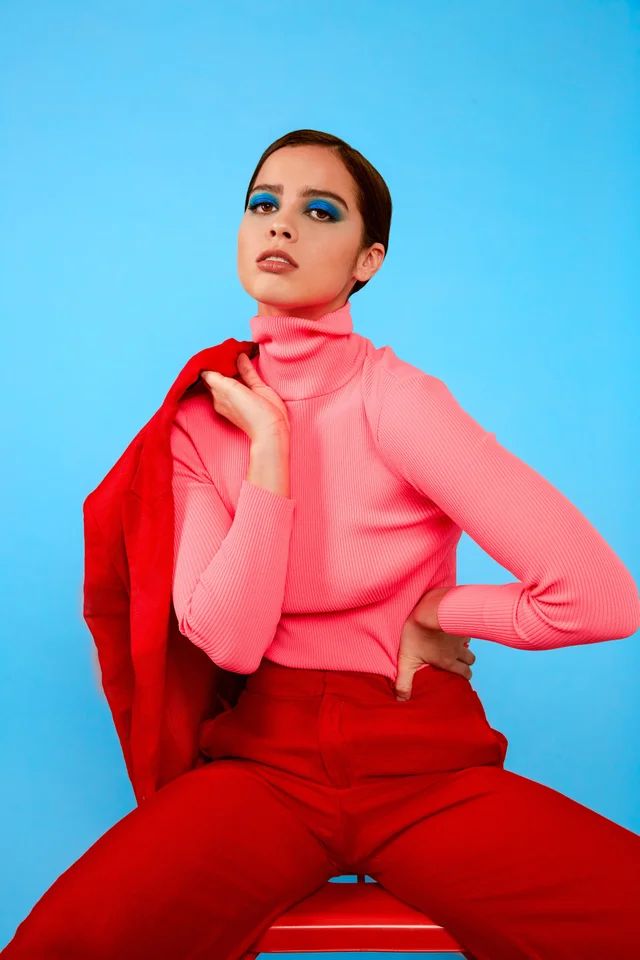 a woman sitting on top of a wooden bench wearing red pants and a pink shirt