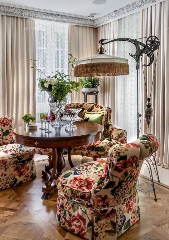 a living room filled with furniture next to a window covered in drapes and curtains