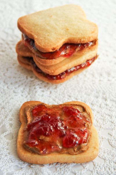 three cookies with jelly filling on them sitting on a tablecloth next to each other