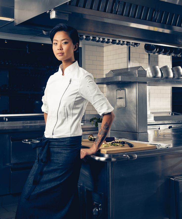 a woman in a chef's uniform standing next to an oven