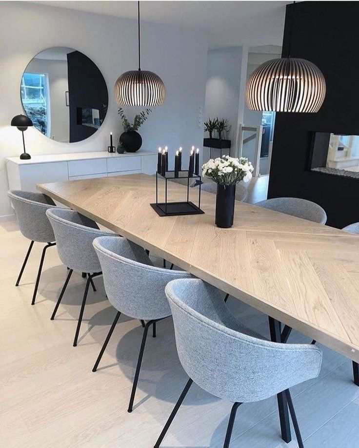 a dining room table with chairs and candles on it in front of a mirror that is hanging above