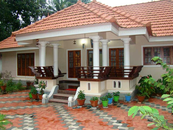 a white house with red tiled roof and porches on the second floor is surrounded by potted plants