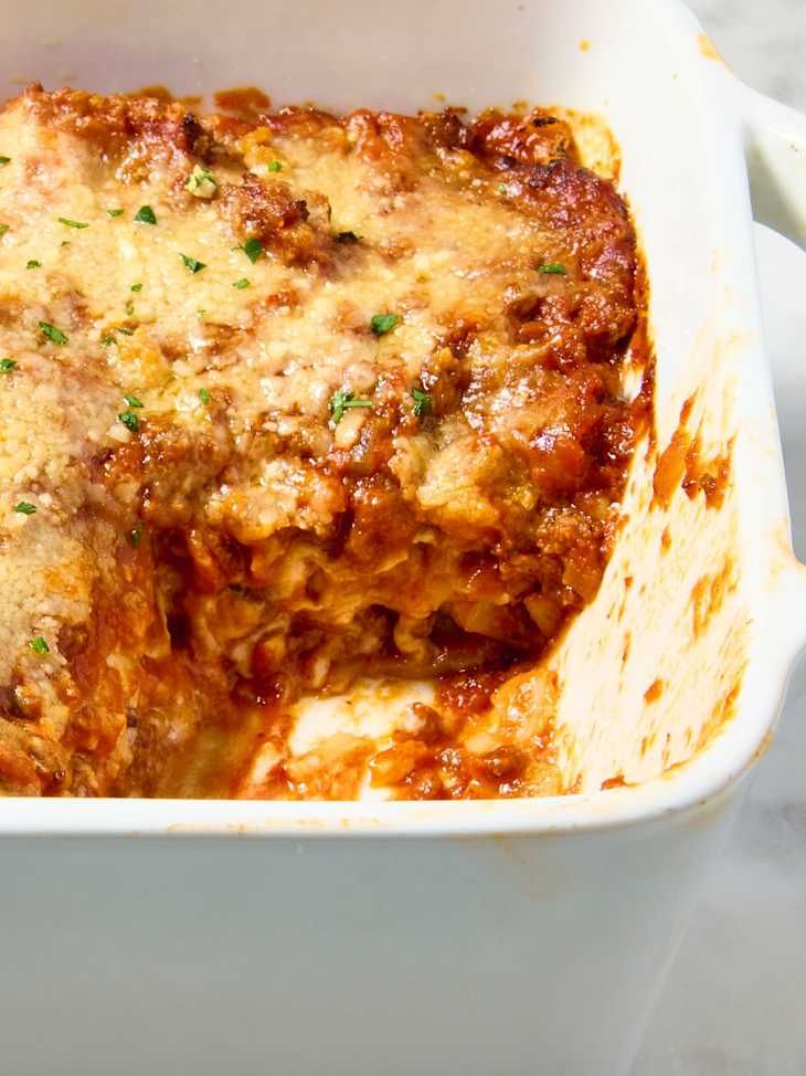 lasagna casserole with meat and cheese in a white dish on a table