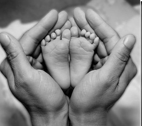 two hands holding the feet of a baby