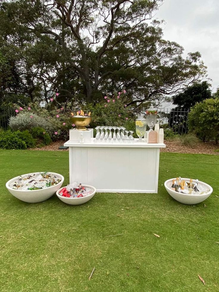 an outdoor bar set up with bowls and wine glasses on the grass in front of it