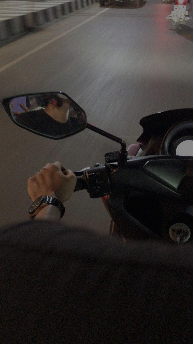 a person on a motorcycle driving down the road with their reflection in the side view mirror