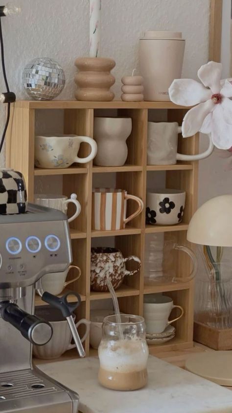 a coffee maker sitting on top of a counter next to a shelf filled with cups and saucers