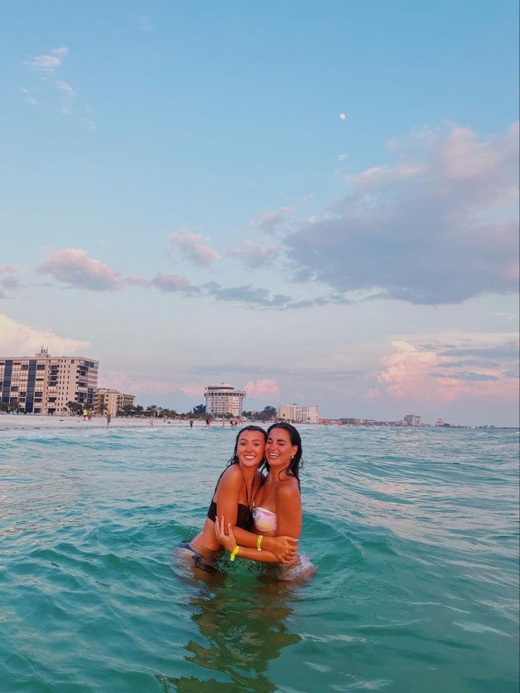 two women in the ocean posing for a photo