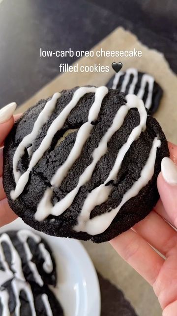 a person holding a chocolate cookie with white icing