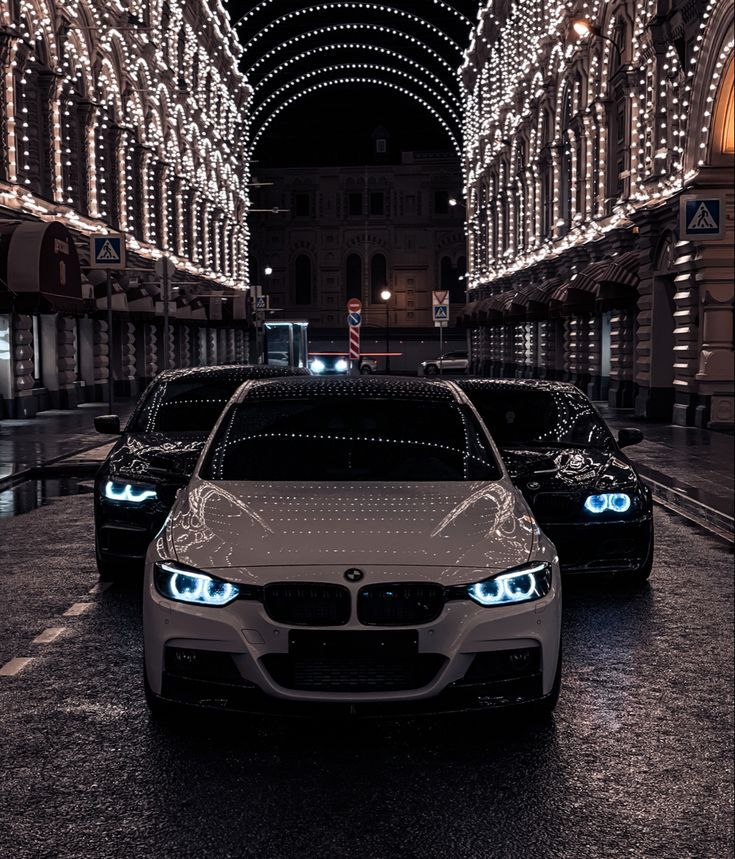 two cars parked in front of each other on a street with lights all around them