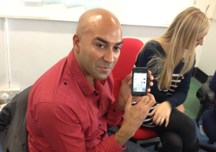 a man sitting in an office chair holding up a cell phone