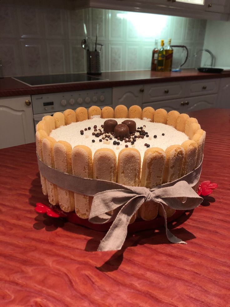 a cake sitting on top of a wooden table covered in frosting and toppings