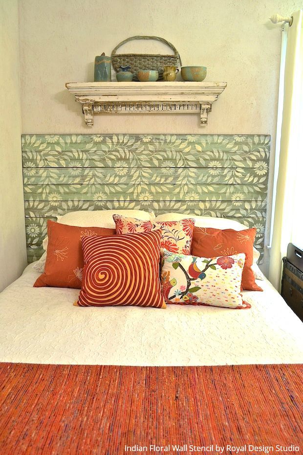 a bed with orange and green pillows on it's headboard in a bedroom