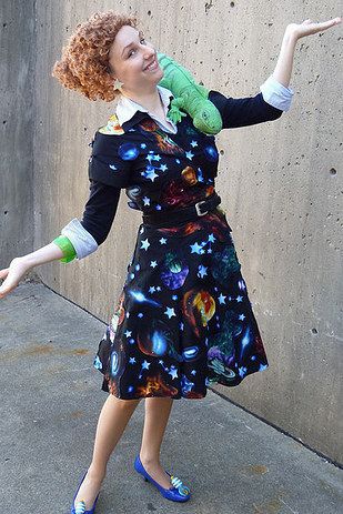 a woman in a black dress holding a green stuffed animal