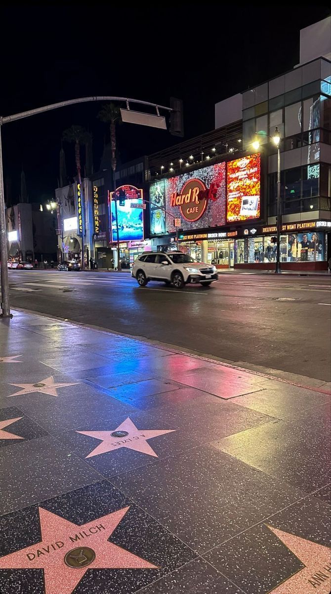 the hollywood walk of fame star is lit up at night, with cars driving by