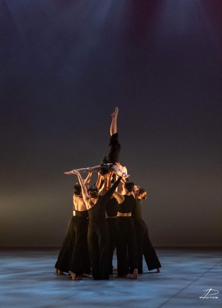 a group of people standing on top of each other with their hands in the air